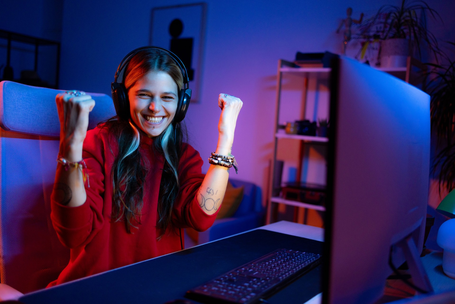 Cheerful woman celebrating her success in eSports over desktop PC at home.