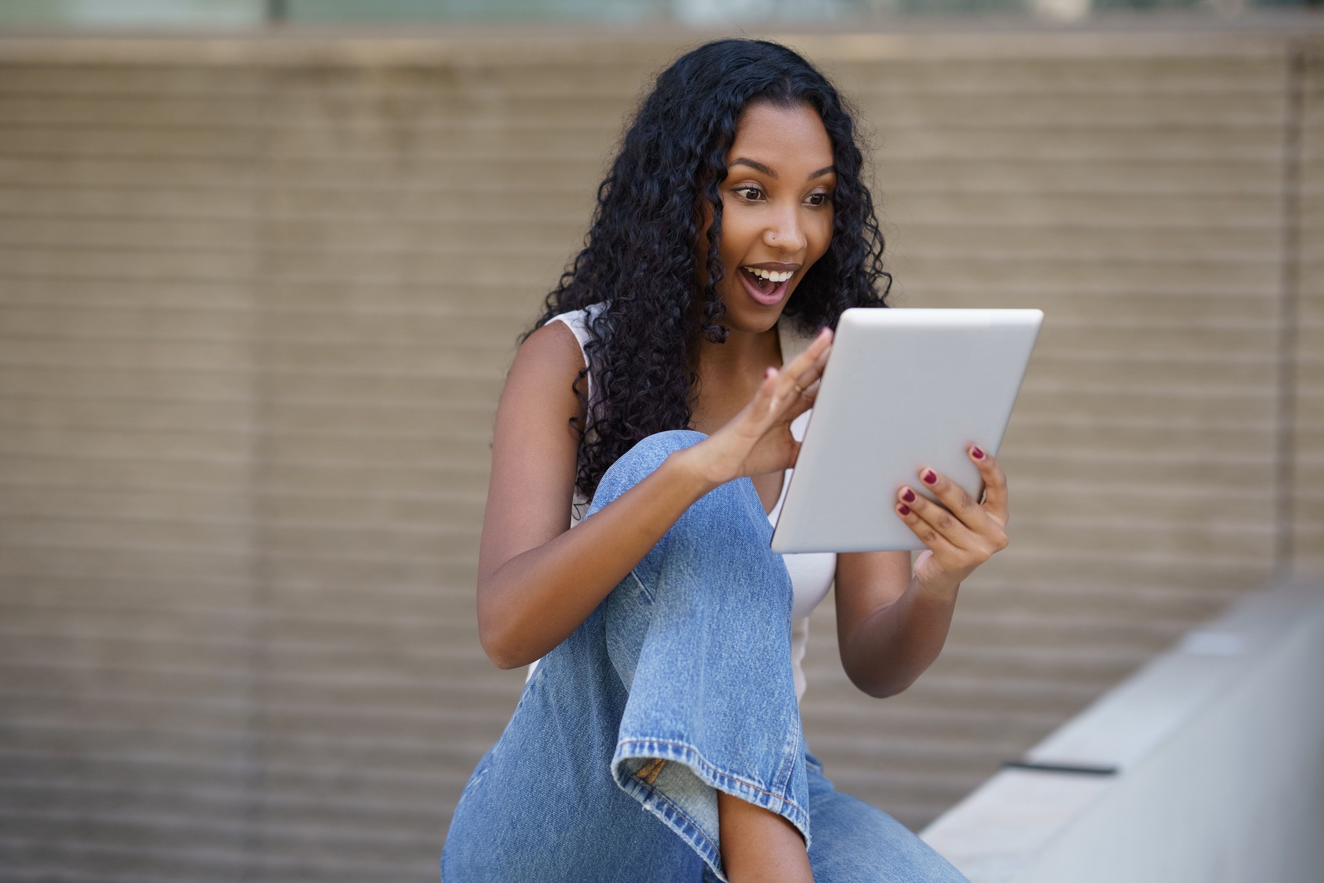 An Excited Young Woman Engaging with a Tablet and Displaying a Joyful Expression on Her Face